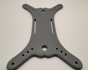 May include: A grey, 3D-printed component with multiple holes and slots. The part has a unique shape with curved edges and a central body. It appears to be a structural element, possibly for a machine or device.