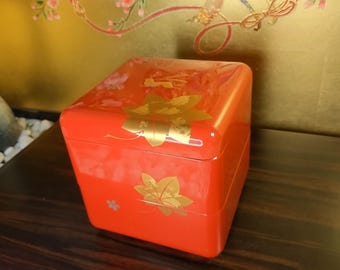 Fiambrera Jubako vintage de resina lacada en rojo, con diseño de conejo de arce dorado en relieve.