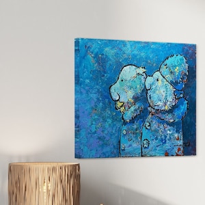 Puede incluir: Pintura abstracta cuadrada con dos figuras con abrigos azules sobre un fondo azul texturizado. La obra de arte cuelga sobre un mueble de madera con una lámpara y objetos decorativos. Un jarrón con ramas está sobre el mueble.
