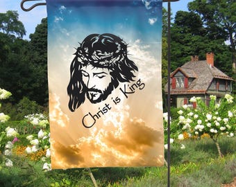 May include: A garden flag with a silhouette of Jesus Christ with a crown of thorns against a background of a cloudy sky. The text "Christ is King" is written below the image.