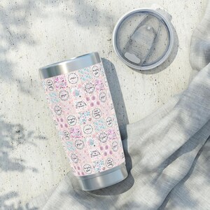 May include: A stainless steel tumbler with a pink and white floral pattern. The tumbler has a lid and is decorated with inspirational quotes. The tumbler is sitting on a white and gray surface.