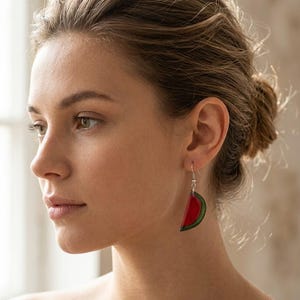 Könnte beinhalten: Hängeohrringe in Form von Wassermelonenstücken mit roten und grünen Details. Diese Ohrringe haben silberne Haken und ein fruchtiges Design. Ein lustiges und farbenfrohes Accessoire.