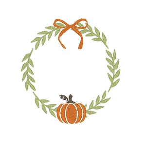 May include: An embroidery design featuring a circular wreath made of light green leaves. At the top, there is an orange bow tied in a simple knot. At the bottom center, there is a small orange pumpkin with a dark brown stem and leaf detail.