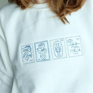 Ras du cou brodé carte postale timbre italien | Blanc et bleu marine | Côtière | Ras du cou d'été | Sweat à capuche Homard Lemons Shells Beach Crewneck