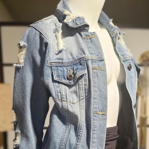 May include: A light blue denim jacket with distressed details and a classic button-up closure.