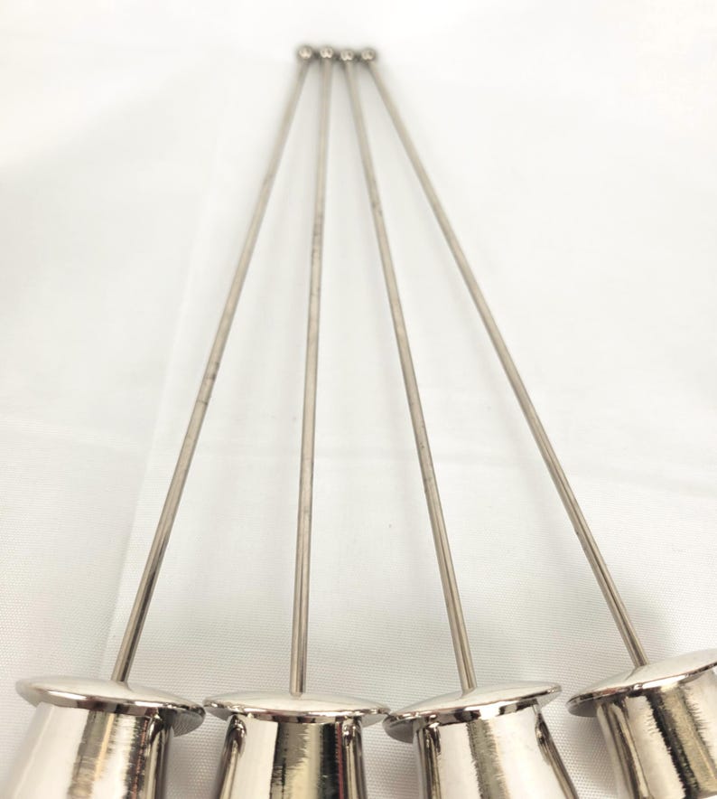 May include: Five silver cocktail picks are displayed. Each pick features a small, cylindrical base and a long, thin stem, culminating in a rounded tip. The picks are set against a white backdrop.