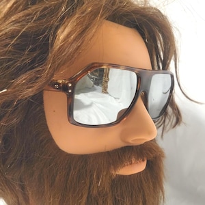 May include: Tortoiseshell-patterned sunglasses with a thick, angular frame and reflective silver-toned lenses. The eyewear features a prominent brow bar and metallic accents at the hinges, providing a bold, structured look with a classic aesthetic.