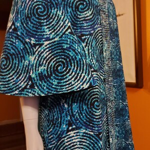 May include: A long blue and white dress with a swirling pattern. The dress has a beaded trim on the side.