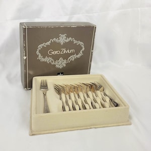 May include: A set of silver forks in a beige felt-lined tray, with a matching box. The box is brown with the text "Gero Zilvium" in a decorative frame. The forks have a detailed handle design.
