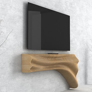 Puede incluir: Un soporte de TV moderno de madera con un diseño ondulado y orgánico. El soporte está montado en la pared y tiene una superficie plana para un televisor. El soporte está hecho de madera marrón claro y tiene un acabado natural.