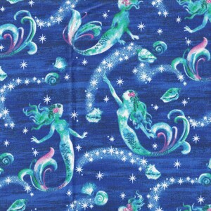 May include: A deep blue fabric featuring a repeating pattern of green and teal mermaids with pink accents. The design includes white starbursts and various seashells scattered across the surface, creating a whimsical underwater scene.