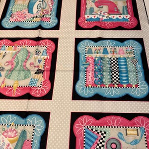 May include: A fabric panel featuring a repeating pattern of sewing-themed illustrations. Each illustration is framed with a black border and a pink or blue border. The illustrations include a sewing machine, spools of thread, a dress form, and sewing tools.