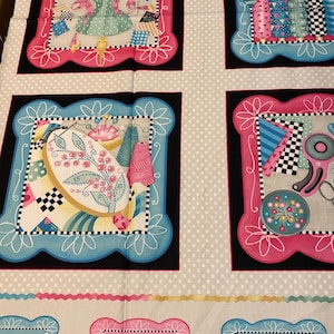 May include: A fabric panel with a white background and a repeating pattern of four squares. Each square features a different sewing-themed design in pink, blue, and black. The squares are surrounded by a white frame with a pink or blue border. The fabric panel has the text "Made with love" in a pink frame at the bottom.