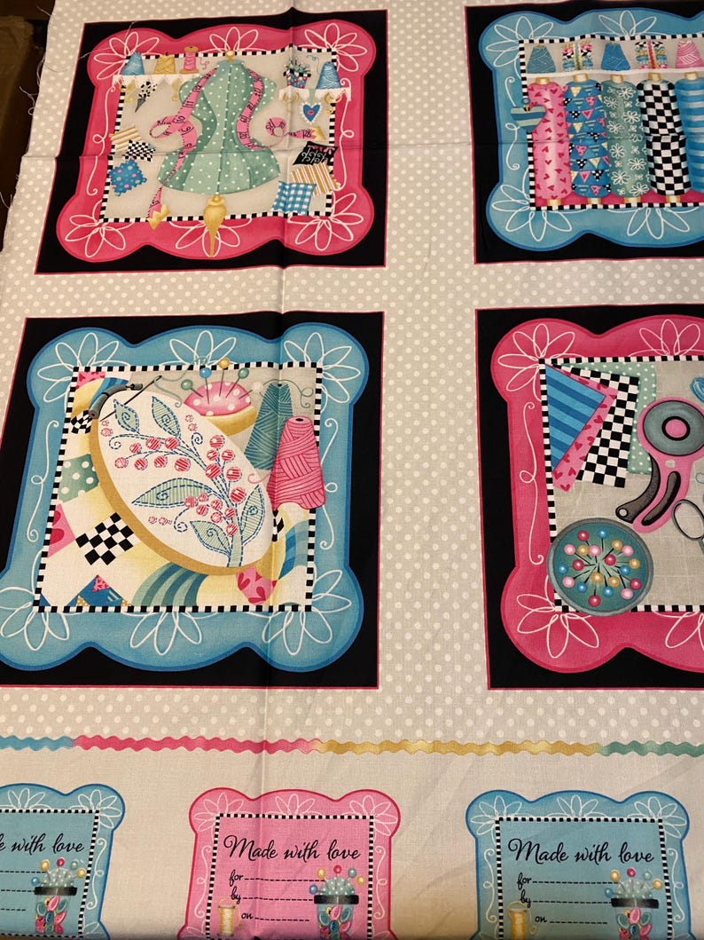 May include: A fabric panel with a white background and a repeating pattern of four squares. Each square features a different sewing-themed design in pink, blue, and black. The squares are surrounded by a white frame with a pink or blue border. The fabric panel has the text "Made with love" in a pink frame at the bottom.