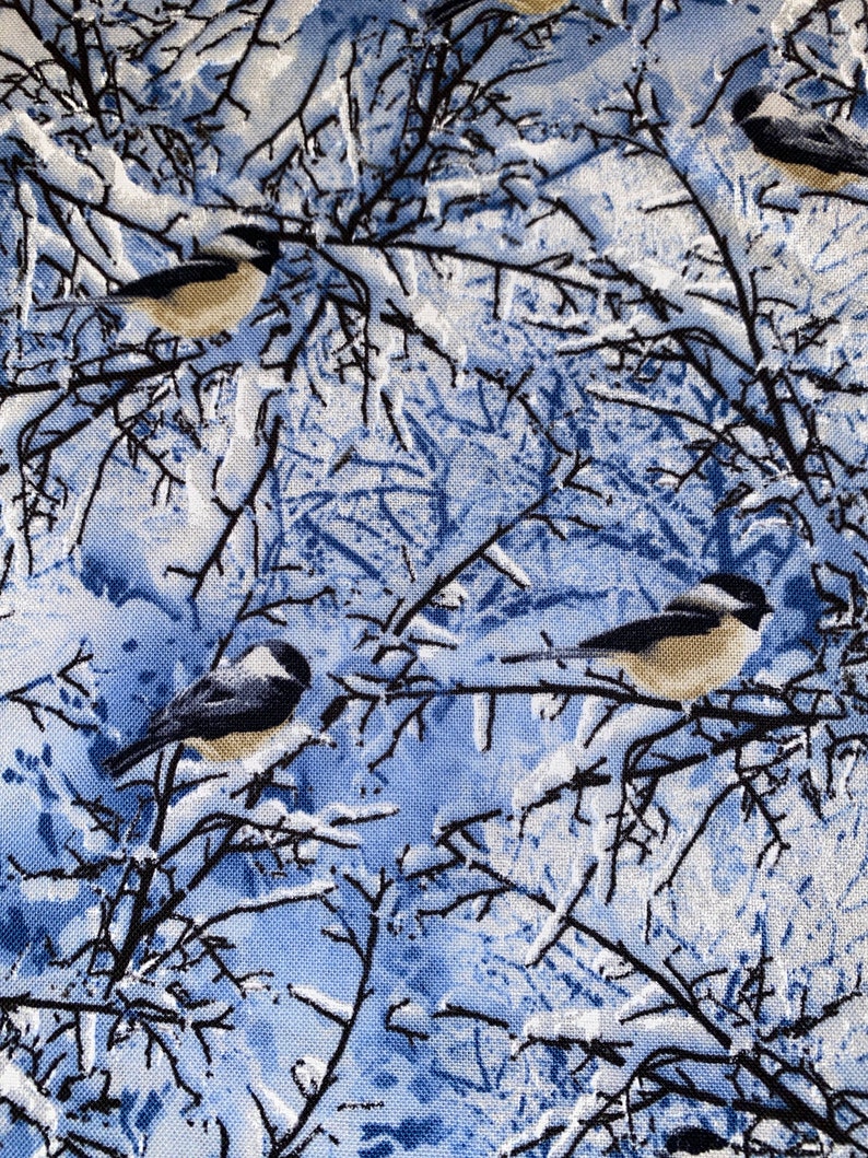 K&ouml;nnte beinhalten: Ein blauer und wei&szlig;er Stoff mit einem sich wiederholenden Muster aus schwarzen &Auml;sten und kleinen grauen V&ouml;geln. Die &Auml;ste sind mit Wei&szlig; bedeckt, das an Schnee erinnert. Die V&ouml;gel sitzen auf den &Auml;sten.