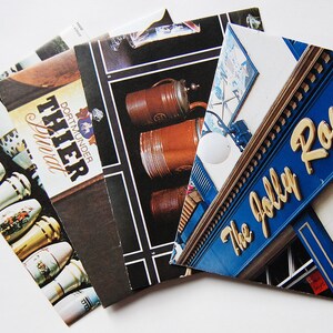 May include: A stack of postcards featuring images of beer steins and a pub sign with the text "The Jolly Roger".