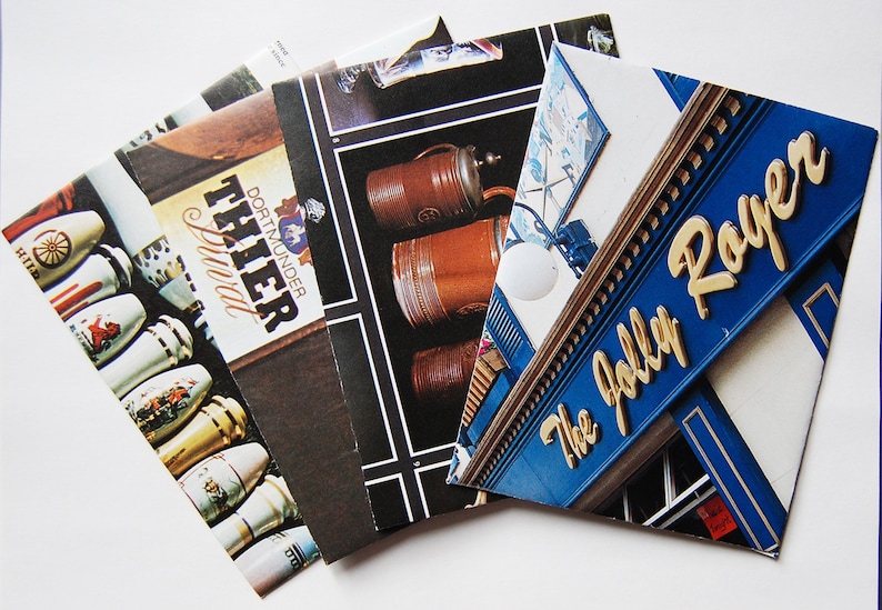 May include: A stack of postcards featuring images of beer steins and a pub sign with the text "The Jolly Roger".