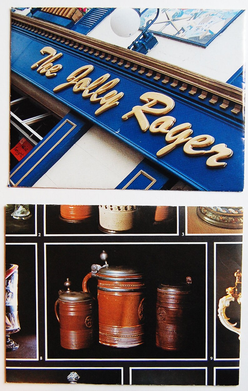 May include: A close-up of a vintage advertisement for The Jolly Roger pub. The sign is blue with gold lettering. The image also shows a collection of vintage beer steins with pewter lids.