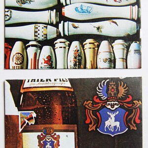 May include: A brown glass bottle of Dortmunder Thier Privat Pils beer with a white label and a red, white, and blue crest. The bottle is in front of a blue and white crest with a red and white deer.