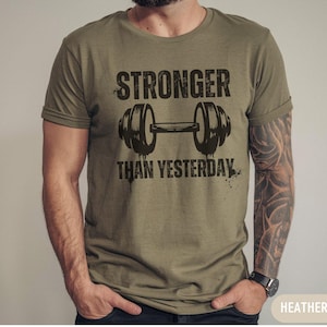 May include: A green t-shirt with a black graphic of a dumbbell and the text "Stronger Than Yesterday".