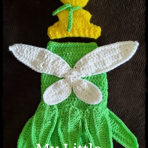 May include: A crocheted Tinkerbell costume for a baby. The costume is green and white with a yellow hat. The hat has a green bow on top. The costume is made of yarn and is very detailed.