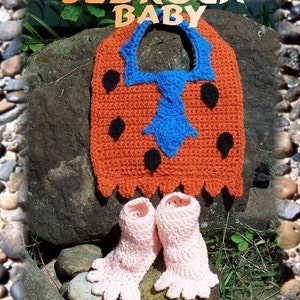 May include: A crocheted baby bib and booties set in orange, blue and black colours. The bib features a cartoon-like design with a tie and the text "Bedrock Baby".