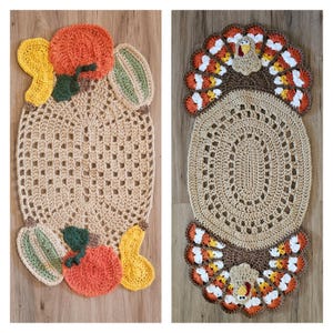 May include: Two crocheted oval table runners, one with a pumpkin theme and the other with a turkey theme. Both runners are beige with brown accents and feature colourful details.
