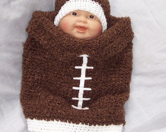 Puede incluir: Un traje de bebé de cocoón de fútbol de ganchillo marrón con costuras blancas y un gorro de ganchillo blanco. El traje está diseñado para parecerse a un balón de fútbol.