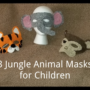 May include: Three crocheted animal masks for children. The masks are an elephant, a tiger, and a monkey. The elephant mask is grey with pink ears. The tiger mask is orange with black stripes. The monkey mask is brown with a tan face.