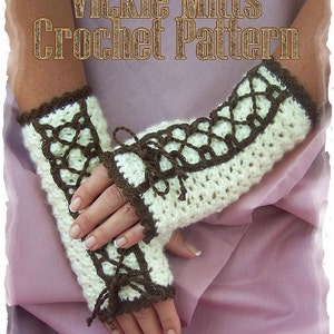 May include: White crochet fingerless mitts with brown crocheted trim and ties. The mitts have a lace pattern and the title "Vickie Mitts Crochet Pattern" is displayed on the image.  Design by Sharon Santerum.