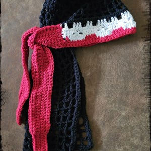 Puede incluir: Patrón de durag de ganchillo con una banda de calavera. El durag es negro con una banda de calavera roja y blanca. El durag está tejido a ganchillo en punto sencillo. "With Skull Band - Easy to Make" está escrito debajo del durag.