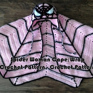 Puede incluir: Capa de crochet rosa y negra con capucha de araña. La capa tiene un patrón a rayas y la capucha tiene un diseño de araña con ojos blancos. El texto "Spider Woman Cape/Wrap Crochet Pattern - Crochet.Pattern" está impreso en la capa.
