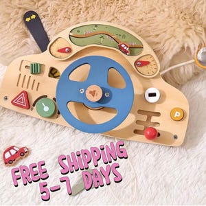 Op de afbeelding: Houten speelgoedauto-dashboard met een blauw stuurwiel, rode en groene knoppen en een kleine rode speelgoedauto. Het speelgoed heeft een verscheidenheid aan functies, waaronder een versnellingspook, een claxon en een snelheidsmeter. GRATIS VERZENDING 5-7 DAGEN.