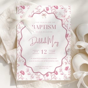 May include: A baptism invitation with a floral design in pink and white. The invitation includes the text "Baptism of our daughter Delilah May" and event details. White baby shoes with bows are in the background.