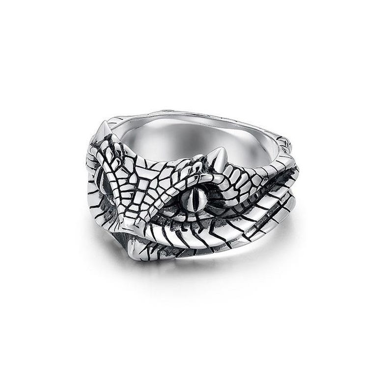 May include: A silver ring with a detailed snake head design. The ring has a textured pattern, with the snake's eye clearly visible. This ring is a bold statement piece, ideal for those who appreciate unique jewellery.