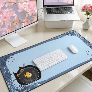 Puede incluir: Alfombrilla de escritorio azul claro con un diseño de gato negro que sostiene una pecera con un pez dorado. La alfombrilla tiene un teclado y un ratón blancos. La alfombrilla tiene un borde azul oscuro con diseños florales y de burbujas.
