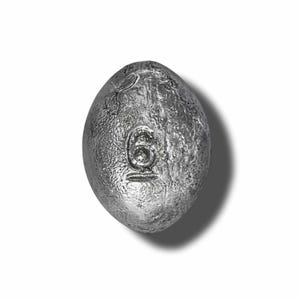 May include: A silver egg-shaped fishing sinker with the number "6" embossed on it.