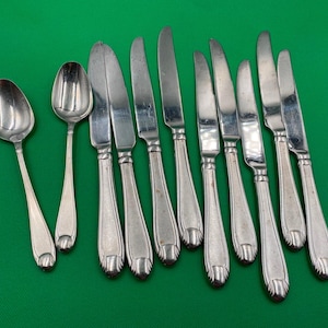 May include: A set of silverware, including spoons and knives, with silver-toned handles and a polished finish. The handles have a decorative design.