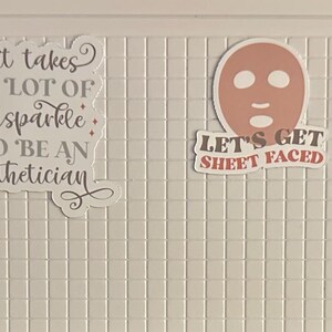 May include: Several stickers with text related to estheticians and skincare. One sticker reads "ESTHETICIAN" in a wavy font. Another says "It takes a lot of sparkle to be an esthetician." A third sticker shows a face mask and the words "LET'S GET SHEET FACED."