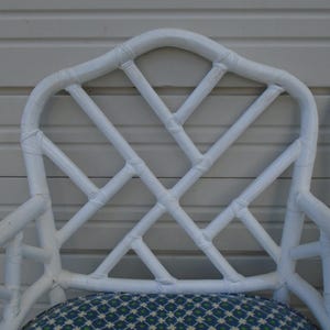 May include: White painted bamboo chair with a diamond pattern and a blue and green patterned cushion.