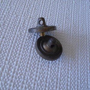 May include: Two antique brass buttons with a hole in the center. The buttons are round and have a raised edge.