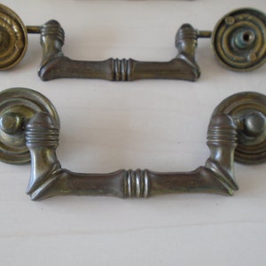 May include: Two antique brass cabinet pulls with a decorative bamboo design. The pulls have a round knob on each end and a center bar.
