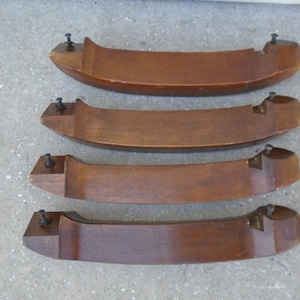 May include: Four wooden chair legs with a dark brown finish and metal screws. The legs are curved and have a slight taper.