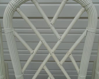 May include: White wicker chair with a diamond-shaped back and a light green cushion. The chair is made of woven rattan and has a simple, elegant design.