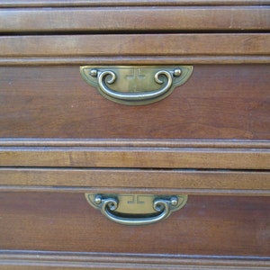 May include: Two wooden drawers with brass handles. The handles have a decorative scroll design. The drawers are part of a wooden cabinet.