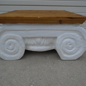 May include: White pedestal coffee table with a wood top. The base is sculpted with a spiral design.