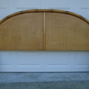 May include: A wooden headboard with a curved top and woven rattan panels. The headboard is brown and has a natural finish.