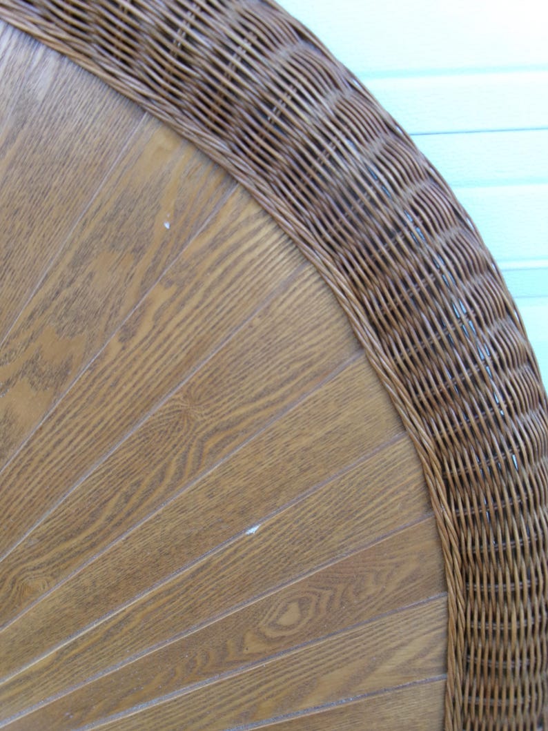May include: Close-up of a section of a brown wicker chair back. The chair back has a wooden panel design with a woven wicker border. The wood has a light brown color with visible wood grain.