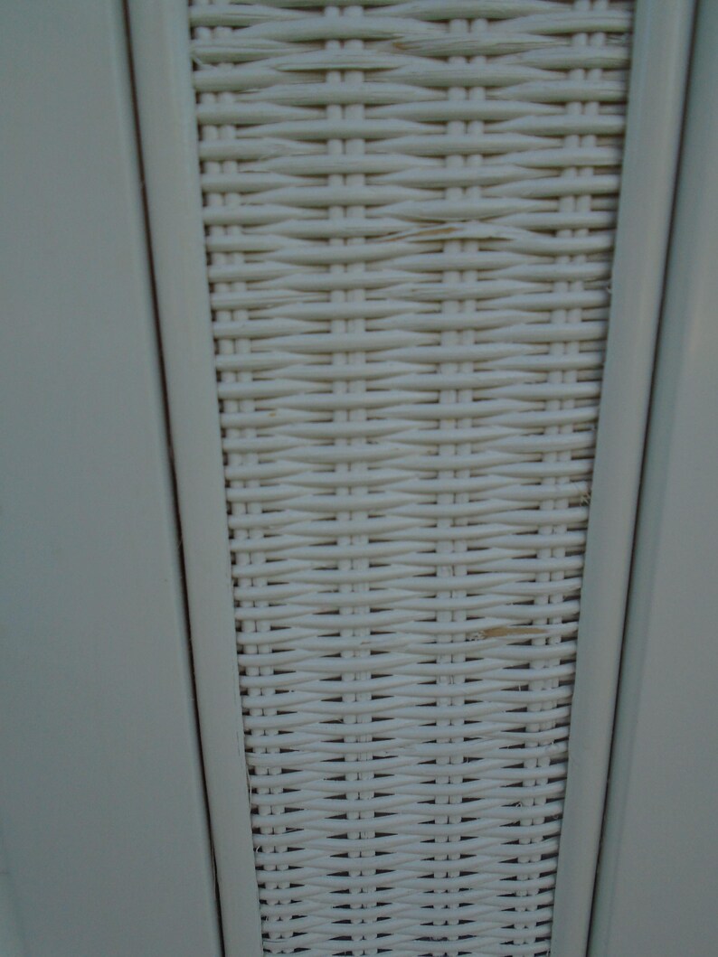May include: Close-up of a section of a white woven wicker pattern. The wicker is tightly woven, creating a textured surface. The frame is a light gray color, and the wicker is a creamy white.