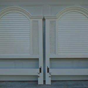May include: Two white headboards with arched tops and horizontal slat detailing. Each headboard has a rectangular center section with horizontal slats and vertical decorative panels. The headboards are made of wood and have a classic design.
